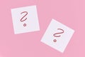 White sticky notes with handwritten question mark symbol in red ink on pink background Royalty Free Stock Photo