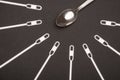 White stirring sticks lying around metal teaspoon on black background.