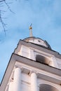 A white stone chapel of an orthodox chirch with a high golden cross going up to the sky. Low angle shot. Silhouette of branches Royalty Free Stock Photo