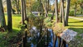 White stone footbridge across small stream in city park in autumn Royalty Free Stock Photo