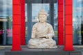 Sculpture of Buddha in meditative pose is located in the middle of red wooden columns Royalty Free Stock Photo