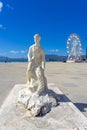 white stone statue representing a fisherman holding a fish as a trophy in the city of VlorÃÂ«, Albania.