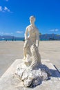 white stone statue representing a fisherman holding a fish as a trophy in the city of VlorÃÂ«, Albania.