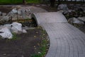 White stone trail and bridge over small pond among stones and rocks in city park. Autumn fallen yellow leaves and red apples Royalty Free Stock Photo