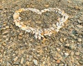 White stones are arranged in the shape of a heart on a ground covered with small rocks and pebbles creating a simple artistic Royalty Free Stock Photo