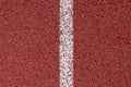 White strip of markings on a red background of rubberized cover of sports grounds and stadiums for outdoor use. Red and white reli