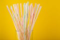 White striped plastic drink straws closeup. Cocktail tubes, in glass, pipe closeup on yellow background. Party concept. Selective Royalty Free Stock Photo