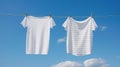 White and striped t-shirts drying on a laundry line, on blue sky background. Clean clothes drying outdoors. Generative AI