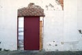 White stucco alley building red door exposed brick Royalty Free Stock Photo