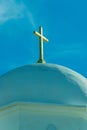 White stucco or cement church dome with visible cross on top and whispy cloud blue sky background in intense lighting Royalty Free Stock Photo