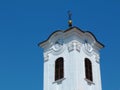 White stucco church clock tower with round clocks and black cross at top. Royalty Free Stock Photo