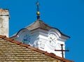 White stucco church clock tower with round clock faces. black handles. old weathered clay roof foreground. Royalty Free Stock Photo