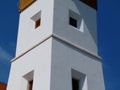 white stucco exterior detail of church tower with small square windows. Royalty Free Stock Photo