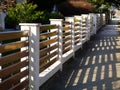 White stucco finished fence piers with horizontal brown metal slats