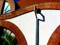 white stucco wall and brick arch with galvanized metal pipe downspout