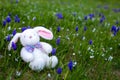 White stuffed bunny sitting outside in a flowerbed