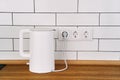 White stylish electric kettle stands on a wooden kitchen countertop