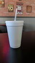 White styrofoam cup with straw on a table. Royalty Free Stock Photo