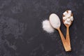 White sugar cubes and granulated sugar in two spoons with white sugar on black table.Flat lay