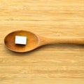 White and sugar cubes in wooden spoon on bamboo cutting board Royalty Free Stock Photo