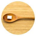 White and sugar cubes in wooden spoon on bamboo cutting board Royalty Free Stock Photo