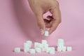 White sugar loaf on the pink floor and the male hand holding the sugar cube Royalty Free Stock Photo