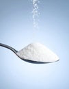 White Sugar Pouring onto Spoon on Light Blue Background Royalty Free Stock Photo