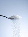 White Sugar Pouring from a Spoon on Light Blue Background Royalty Free Stock Photo