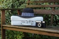 White suitcase, the old camera and hat on a bench in a garden Royalty Free Stock Photo