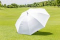 The white sun umbrella place on green grass golf course using for sun protection. Royalty Free Stock Photo