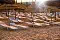 White sunbeds on the evening empty beach under straw umbrellas. Sunset sun on the sea in Arab country, Tunisia, Africa, middle