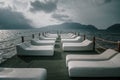 White sunbeds stand on the pier. Nice pier. Sea coast. Mountains in the background. Royalty Free Stock Photo