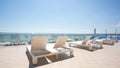 White sunbeds at the terrace of a hotel near the tropical beach. A lot of white deck chairs near the sea beach. Summertime. Royalty Free Stock Photo