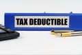 On a white surface, a calculator, a pen and a folder with the inscription - TAX DEDUCTIBLE