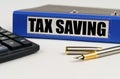 On a white surface, a calculator, a pen and a folder with the inscription - Tax Saving