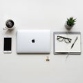 A white surface features a closed silver MacBook, iPhone, and Royalty Free Stock Photo