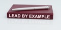 On a white surface lies a pen and a notebook with the inscription - LEAD BY EXAMPLE Royalty Free Stock Photo