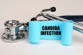 On a white surface lies a stethoscope and a blue roll of paper with the inscription - Candida Infection