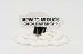 On a white surface are pills and torn paper with the inscription - How to Reduce Cholesterol Royalty Free Stock Photo