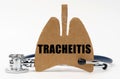 On a white surface are a stethoscope and a cardboard figure of a lung with the inscription - Tracheitis