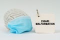 On a white surface there is a brain with a blue mask and a notepad with the inscription - Chiari malformation Royalty Free Stock Photo