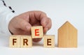 On a white surface there is a model of a house, next to it a man has placed cubes with the inscription - FREE Royalty Free Stock Photo