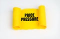 On a white surface, a yellow scroll of paper with the inscription - Price Pressure