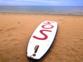 white surfboard on the sand of a beach called Playa Honda - Lanzarote island - Spain. The surfboard shows in red the letters sos Royalty Free Stock Photo