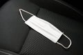 White surgical mask lying on the passenger seat of a car. Covid-19 and isolation illustration