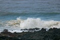 White surf breaking behind black rocks. Royalty Free Stock Photo