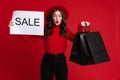 White surprised woman posing with shopping bags and sale placard