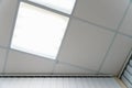 White suspended ceiling with square fluorescent lights in an office space. Design and details of a modern ceiling and lighting