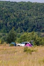 white car and three tourist tents in tall dry yellow grass