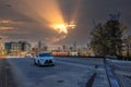 A white SUV driving over a freeway overpass in the city with skyscrapers and office buildings in the city skyline